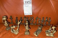 Overview of 15 brass figurines arranged on orange background showing varying sizes and activities.