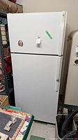 Front view of closed unit showing white GE refrigerator with top freezer.