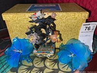 Photo showing the two blue Murano glass flowers and the cloisonne style vase with flowers in front of a patterned box.