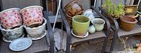 Wide view of all 11 pots and one saucer arranged on two metal patio chairs.