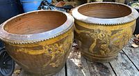 Pair of two large ceramic plant pots side by side on wooden surface
