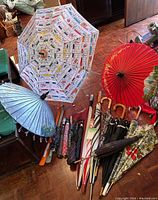 Wide view of all umbrellas and parasols arranged on the floor showing multiple items and details.
