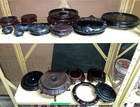 Two shelves with multiple hardwood and ceramic stands visible