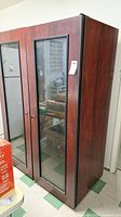 Full height view of tall wine fridge with wood finish and glass doors showing side and front perspectives.