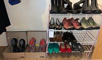 Overview of 13 pairs of women's footwear including boots, sandals, cycling shoes and casual shoes arranged on shelves and boxes.