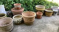 Front view of unglazed terracotta planters alongside painted ceramic pots