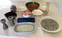 Full view of colorful bowls, candlestick holders, and ceramic dishes arranged on a light surface