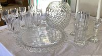 Wide shot showing large vase, 7 crystal drinking glasses, decorative serving plate, and additional glassware