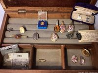 Photo showing entire collection arranged in wooden box, including trilobite cufflinks, pins, clips and other stone insets.