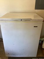 Front view of white Kenmore chest freezer with visible lock on lid and slightly worn exterior.