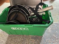 Large green storage bin containing several cookware pieces including Lagostina frying pans