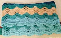 Close-up of the knitted wave pattern with scalloped edges in varying shades of blue and cream.