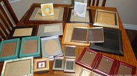 Full collection of assorted picture frames arranged on a table showcasing various sizes, colors and materials