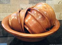 Large wooden salad bowl with six smaller wooden bowls nested inside it.