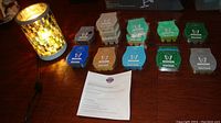Photo showing electric wax warmer lit on a table with multiple wax bars of various scent colors and instruction sheet laid out beside it.