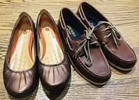 Pair of copper-coloured Clarks slip-on flats and brown Sperry Top-Siders men's boat shoes on wooden floor.