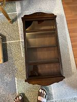 Top-down view of the wall display cabinet closed, showing glass front and wooden frame.