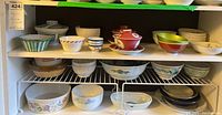 Three-shelf cabinet view of assorted bowls and plates
