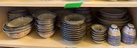 Shelves holding multiple stacks of Asian porcelain bowls and teacups, showing various sizes and matching blue and white decorations