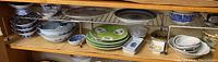 Shelf with stacks of various blue and white and colored porcelain bowls and plates