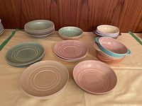 Full lot showing Branksome China plates and bowls in pastel colors, including stacked plates and two handled bowls.