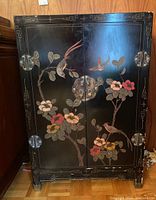 Front view of black lacquer cabinet showing bird and floral motifs