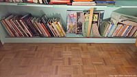 Wide view of lower shelf filled with many Asian recipe cookbooks including some about Chinese cuisine.