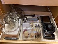 Overall view showing food processor base, work bowl, lid, blade/disc set, mandoline slicer, and pasta attachments laid out in drawer