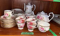 Full shelf view of Royal Albert American Beauty tea set including pots, cups, saucers and plates