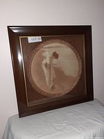 Front view of the antique framed print featuring a woman holding seashells with wood veneer mat and solid wood frame.