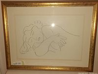 Front view of the framed line drawing print of a sleeping woman, showing gold frame and matting.