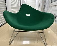 Front view of green upholstered asymmetrical shell lounge chair with chrome sled base.