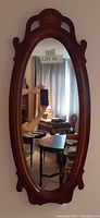 Front view of the oval mirror showing cherry veneer frame, decorative inlay at the top, and reflective surface.