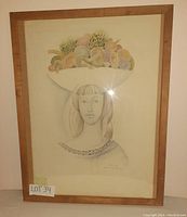 Full view of the framed watercolour drawing showing the woman with a bowl of fruit on her head, housed in a simple wooden frame.
