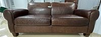 Front view of leather sofa showing overall design, cushion condition and rolled arms