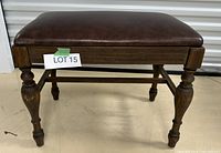 Front side view of the foot stool showing leather cushion and carved wooden legs