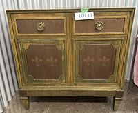 Front view of mid-century music cabinet with decorative floral panels and golden-brown finish
