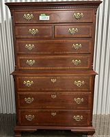 Front view of Queen Anne style chest-on-chest dresser with five drawers, carved crown molding and bracket feet.