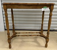 Front view of walnut foyer table showing turned legs and scalloped tabletop edge.