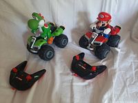 Two Nintendo Mario Kart character radio control toy cars, Mario and Yoshi, with two black remote controllers showing lot contents