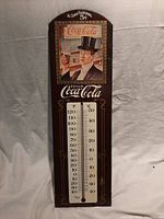 Full view of the Coca Cola thermometer showing the dual temperature scales and advertising image.