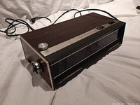 Side angled view showing the Wynford Hall clock radio with wood grain panel on top, the analog tuning dial on the left side, and the digital clock display on the front right.