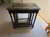Side view showing all three nesting tables nested together, barley twist legs visible, tabletop edges scalloped
