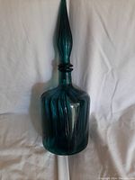 Full view of blue-green Italian Empoli glass decanter with stopper in place, showing ribbed texture and tall narrow stopper.