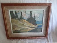 The framed landscape painting shows the riverbank with trees and water, captured in soft colors and brushstrokes, framed in a carved wooden frame with beige fabric matting.