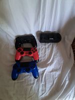 Top down view of three PS4 controllers in black, red, blue alongside dual charging dock showing controller details and dock slots.