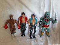 Photo showing four vintage action figures including Mr. T, two John Rambo, and Thundercats Mumm-Ra on white background