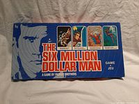 Photo of the front of The Six Million Dollar Man board game box by Parker Brothers, showing the title, actor's face illustration, and four illustrated action scenes