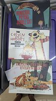 Photo showing three Calvin & Hobbes books stacked: 'Homicidal Psycho Jungle Cat', 'The Calvin and Hobbes Tenth Anniversary Book', and 'There's Treasure Everywhere'