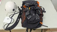 Image showing the white Black Diamond helmet, black MEC ropebag with orange accents, and black gear strap placed on a table.